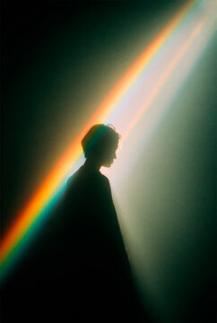 Mystical Silhouette of a Person in Profile Illuminated by a Vibrant Diagonal Rainbow Light Beam, Creative Film Grain Portrait