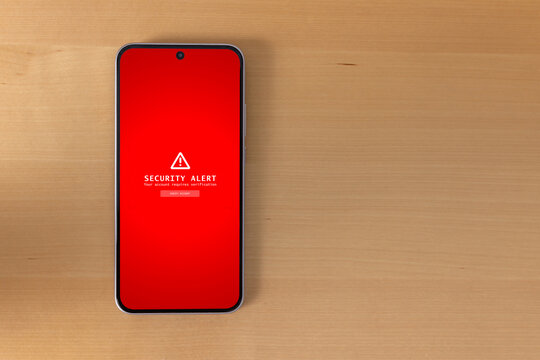 Top view of smartphone displaying security alert on wooden desk