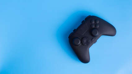 Diagonal flat lay of black wireless gamepad controller on blue background with copy space. Ideal for esports and gaming ads.  © wibiwisnu