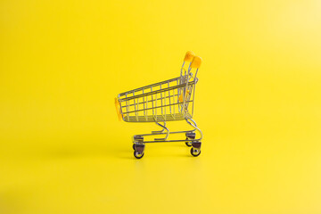 Side view of empty yellow miniature shopping cart on yellow background. Great for ecommerce retail online shopping and consumerism concepts.  © wibiwisnu