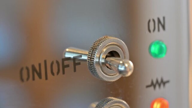 Close-up video of a person flipping a switch to turn on a machine, showing the activation of industrial equipment and the start of a mechanical process.