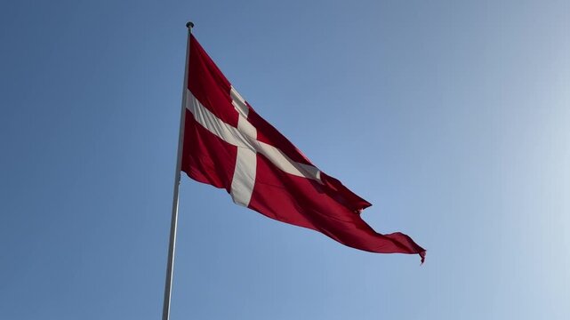 National flag of Denmark waving against blue sky background