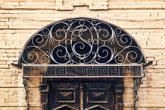 Ornate vintage wooden doorway with wrought iron scrollwork set into brickwork
