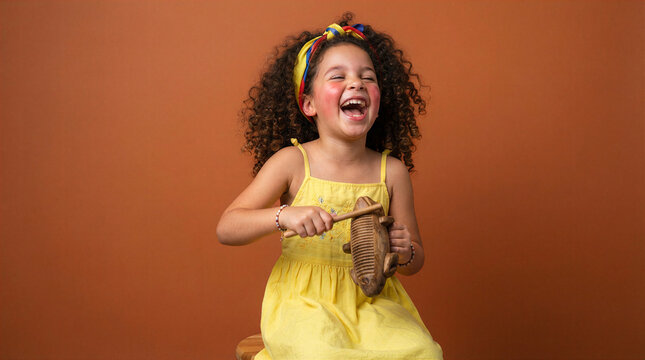 Joyful young girl with curly hair plays a wooden frog guiro instrument