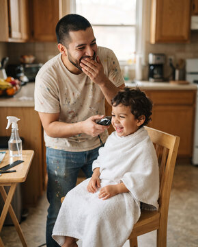 Laughing Father Giving Toddler Son Haircut at Home