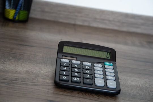 Black electronic calculator displaying zero on wooden background with copy space