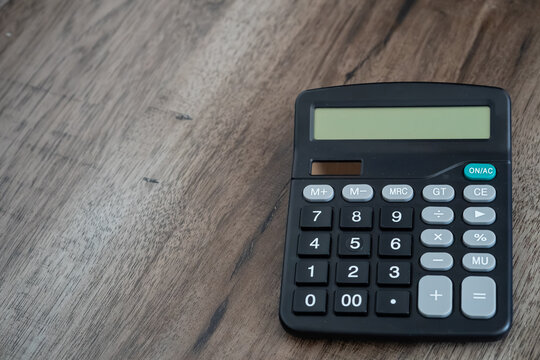 Black electronic calculator on wooden background with copy space