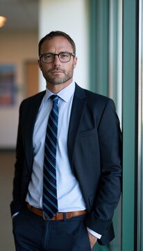 Male education administrator standing by glass wall in modern hallway