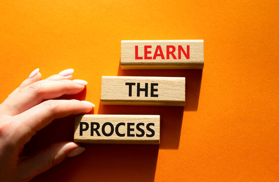 Learn the process symbol. Concept words learn the process on wooden blocks arranged as steps. Businessman hand arranging wooden blocks. Learning and development concept. Orange background. Copy space.