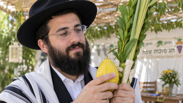 Sukkot celebration with Jewish man holding etrog and lulav Four Species inside traditional sukkah