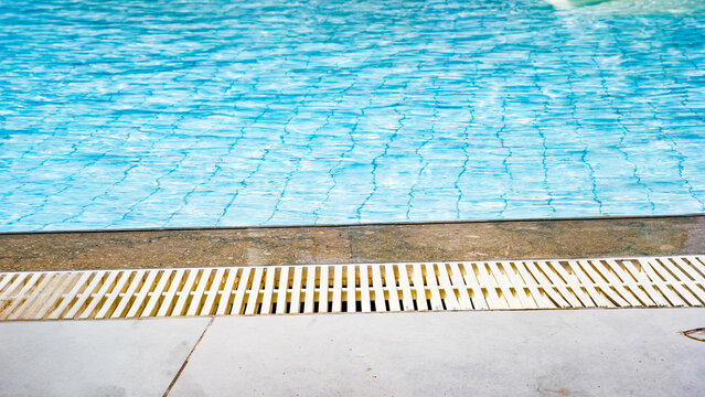 A serene view of a shimmering blue swimming pool with textured tiles and a clean, lined edge.