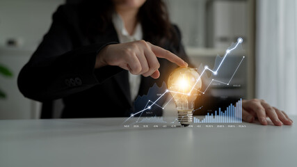 A business professional interacts with a light bulb while showcasing upward graph projections, illustrating innovation and growth in a competitive market. Scalp © InfiniteFlow
