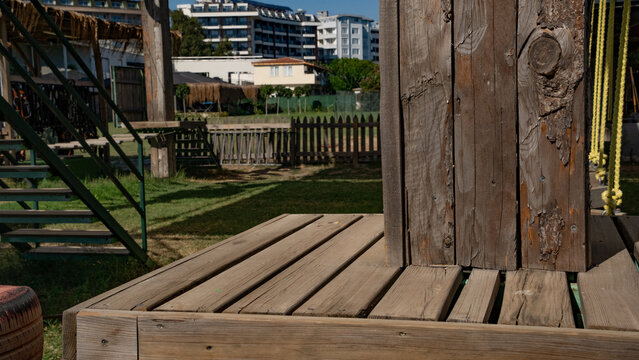Wooden playground structure in a sunny park setting, showcasing natural textures and vibrant green grass.