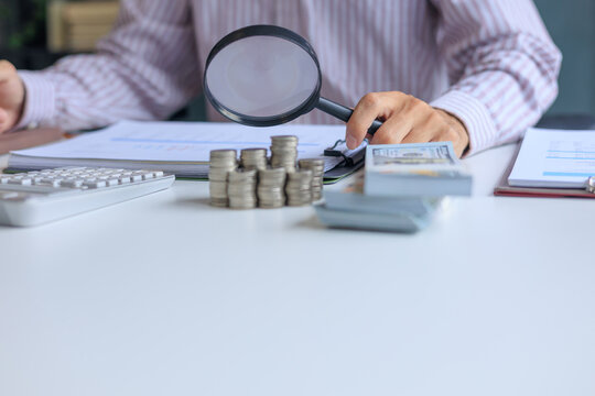A person using magnifying glass to conduct a financial audit and bookkeeping review. financial analysis and forensic accounting to prevents leaks and invoicing errors.