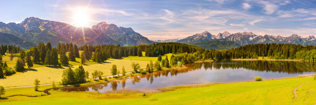 Panorama Landschaft im Allg&auml;u mit saftigen Fr&uuml;hlingswiesen und Blick &uuml;ber den Hegratsrieder See zu den Alpen - FOTOMONTAGE