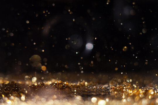 Macro photo of gold glitter sparks bokeh on black background