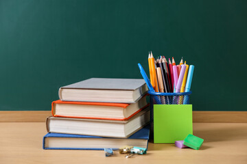 Different stationery and books on wooden table near chalkboard © New Africa