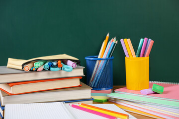 Different stationery and books on table near chalkboard, closeup © New Africa