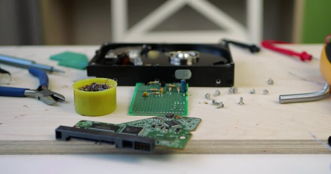 Tools and electronic components spread across workspace. Technicians repair devices, focusing on circuit boards and gadgets. Creative atmosphere fosters innovation and problem-solving