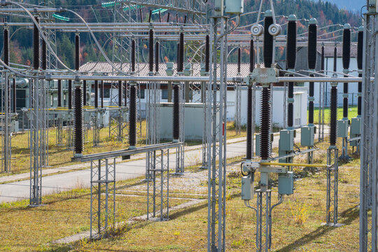 Am Wasserkraftwerk an der Isar bei Kr&uuml;n steht ein elektrisches Umspannwerk mit Transformatoren, Isolatoren und Stromleitungen.