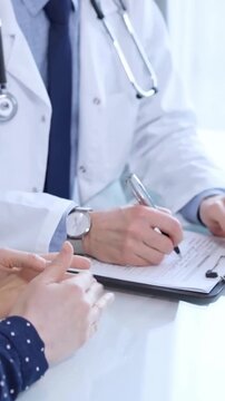 Doctor and patient are talking in clinic after health exam. Male physician is sitting and discussing test results with a senior woman. Medicine and pharmacy