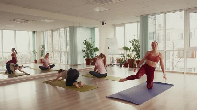 Women enjoy a yoga class together in a bright fitness studio.