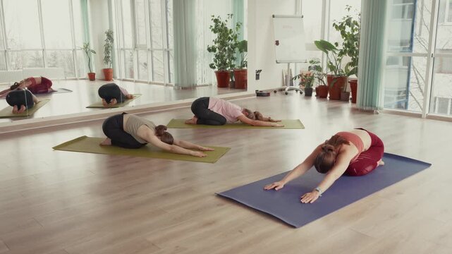 Women relaxing and enjoying a yoga class in a bright studio.