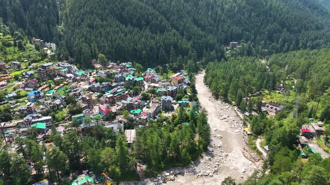 High-angle aerial Orbit shot capturing Parvati River beside Kasol town, Himachal Pradesh India