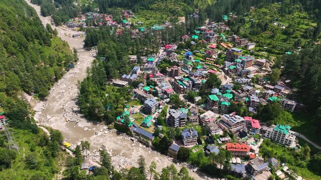 Cinematic drone Orbit shot of Parvati River Valley with Kasol town and lush Deodar cedar forests in Himachal Pradesh India