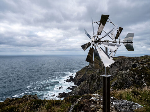 Kinetic wind sculpture on coastal cliff overlooking the ocean