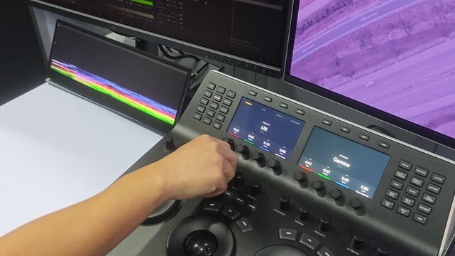 Color grading. Professional colorist operating video color grading control panel. with trackballs knobs and display controls for adjusting color gamma and visual tones in video post production.