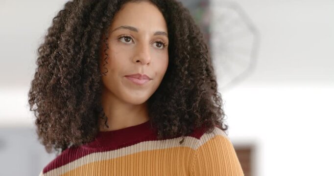 Lens tilting up, showing Adult African American woman in kitchen in striped sweater, attentive gaze