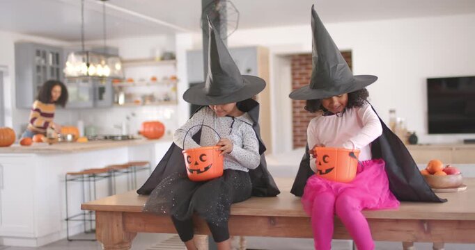 African American child girls rummaging in pumpkin buckets for candy, caregiver arranging pumpkins