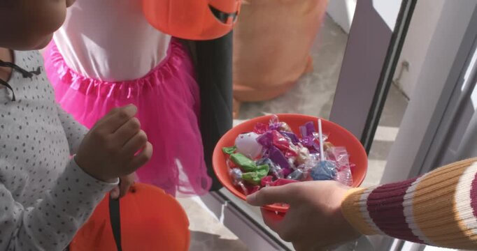 African American child girls with pumpkins reaching for tray as adult offering candy, copy space