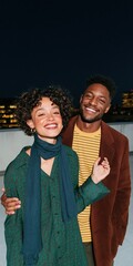 Obraz premium Smiling couple on a rooftop at night portrait with city skyline and scarves for lifestyle banner and background design use