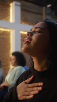 Young African American woman singing passionately during Christian worship as moving camera reveals woman joining in heartfelt praise celebrating diversity united through faith