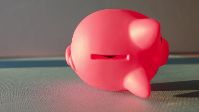 Piggy bank rolling and spinning on a flat surface during the morning light