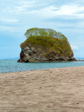 Rocky island with green trees in tropical ocean