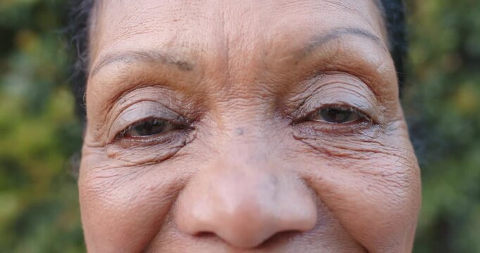 On camera start woman's eyes are lowering and blinking, squinting against daylight in garden
