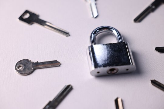 Different keys and lock on light grey background, closeup