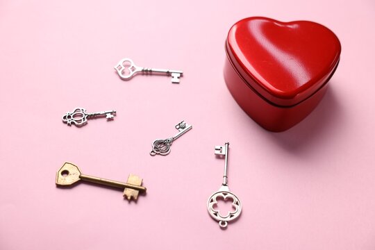 Choice concept. Heart shaped box and different keys on pink background, closeup