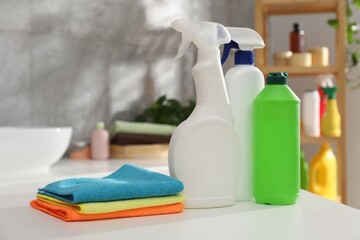 Different cleaning products and supplies on white table in bathroom, closeup