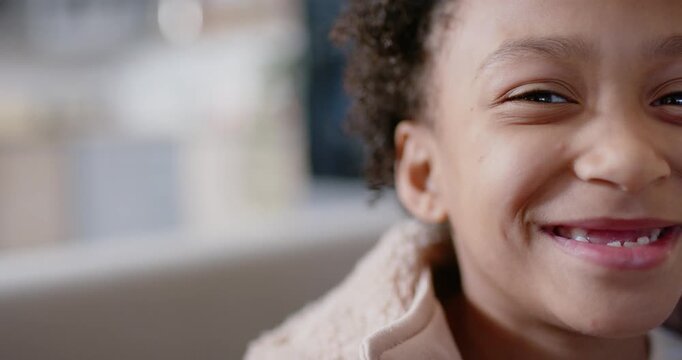 African American child smiling leaning as off-camera cue causing laugh on couch in coat, copy space