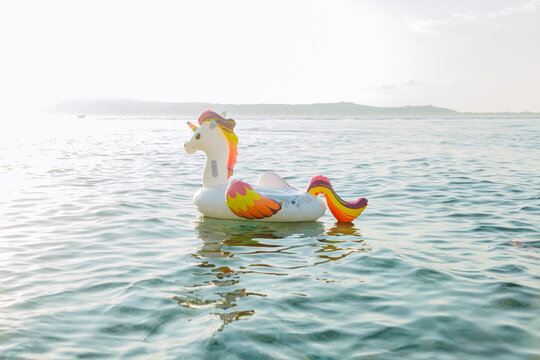 Inflatable Unicorn Float Drifting in Calm Sea Water at Sunset