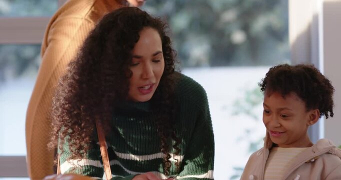 African American family choosing small pumpkin at stall, woman pointing, girl touching