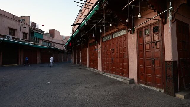 Marrakech, morocco. August 10, 2026. Lone man walking through a deserted narrow street in the old medina of marrakech, morocco, with all the souk shops closed at dawn