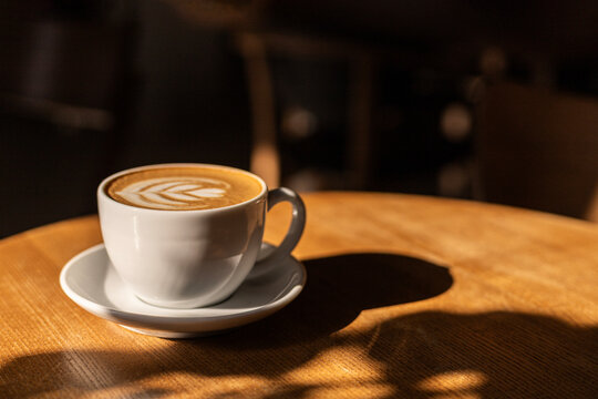 Latte art coffee cup on a sunlit cafe table