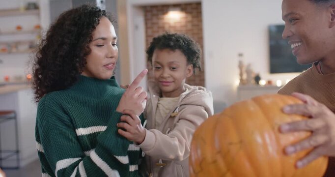 African American family with son reacting at home as man bringing pumpkin and knife for carving