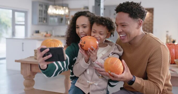 African family taking fall pic in kitchen mom using phone child holding lantern, pa lifting pumpkin