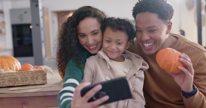 Family of three at wood table, woman extending phone, taking selfies capturing pumpkin moment